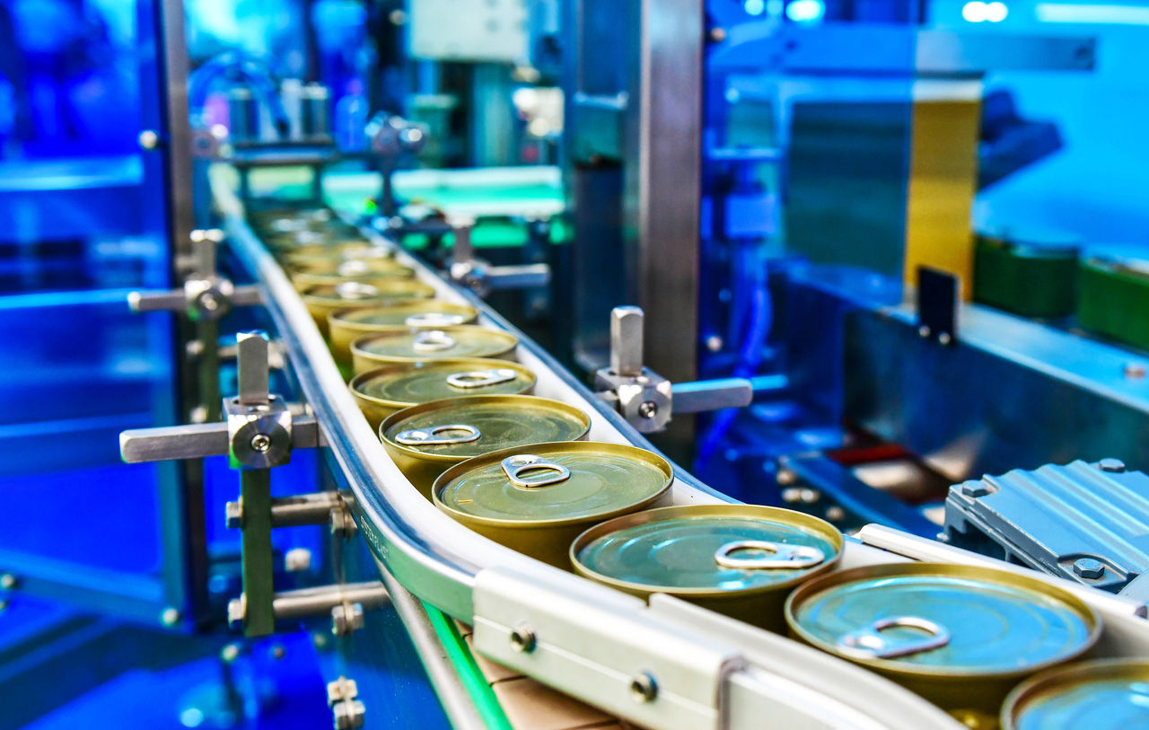 Canned food products on conveyor belt in distribution warehouse.